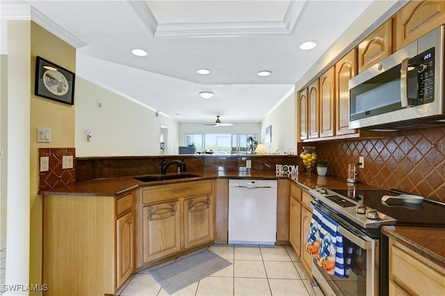 kitchen with stainless steel appliances, dark countertops, crown molding, and a sink