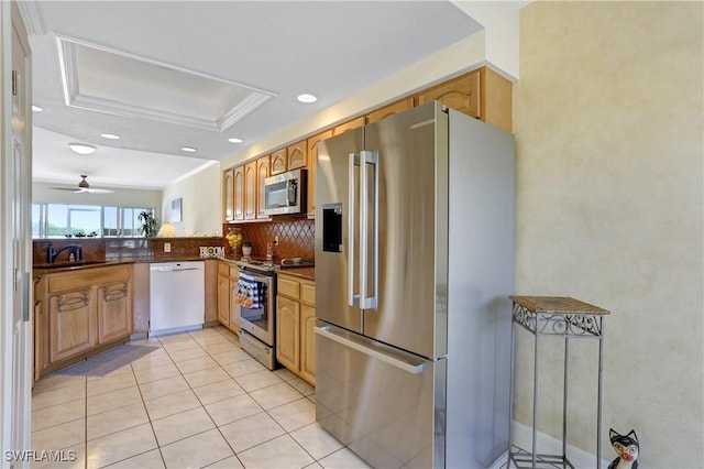 kitchen with light tile patterned floors, stainless steel appliances, tasteful backsplash, dark countertops, and a raised ceiling