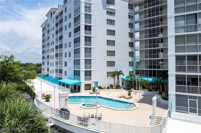 community pool with a community hot tub, a patio, and fence