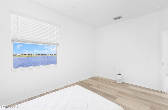 unfurnished room featuring a water view and light wood-type flooring