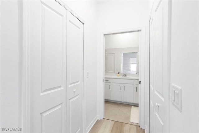 hallway with light hardwood / wood-style floors and sink