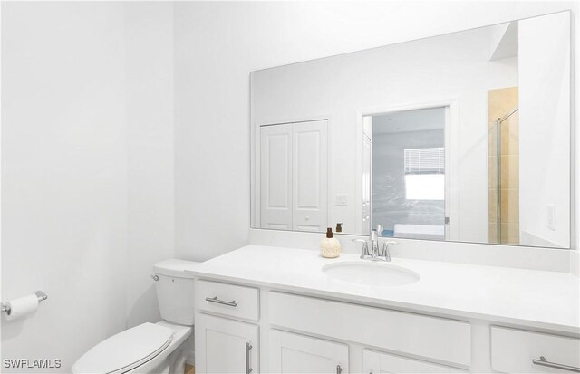 bathroom with vanity, a shower with shower door, and toilet