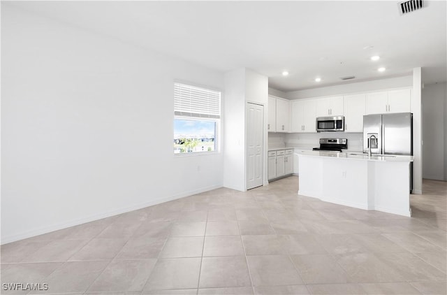 kitchen with stainless steel appliances, an island with sink, and white cabinets