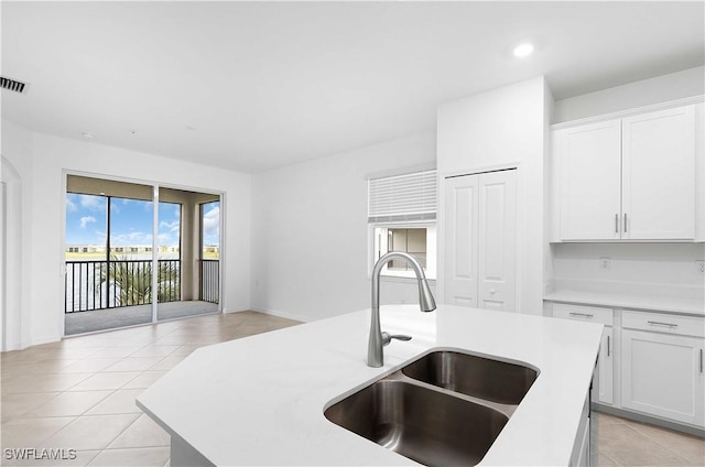 kitchen with light tile patterned flooring, sink, and white cabinets