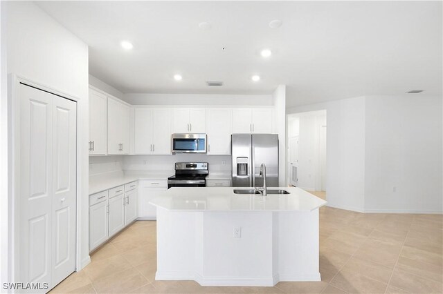 kitchen featuring sink, white cabinetry, a center island with sink, light tile patterned floors, and appliances with stainless steel finishes