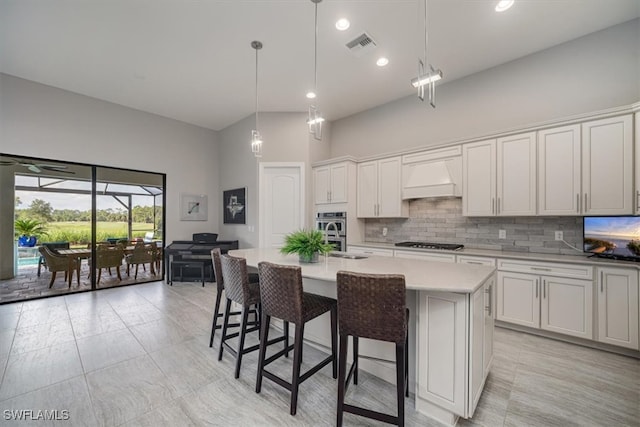 kitchen with white cabinets, an island with sink, decorative light fixtures, and gas cooktop