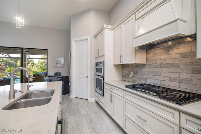 kitchen with sink, white cabinetry, decorative backsplash, appliances with stainless steel finishes, and premium range hood