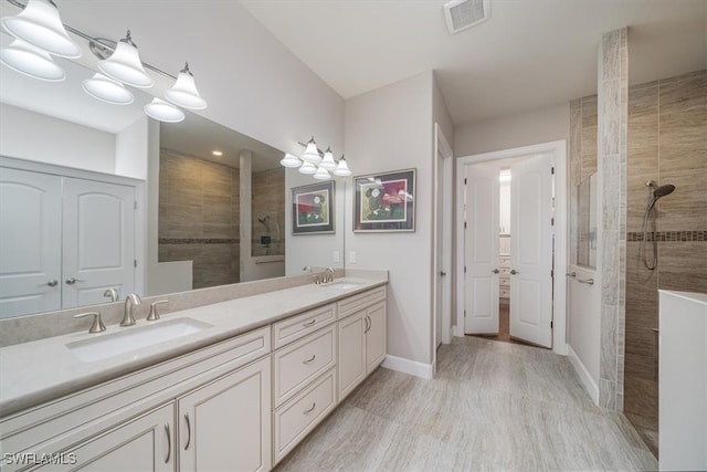 bathroom featuring wood-type flooring, vanity, and tiled shower