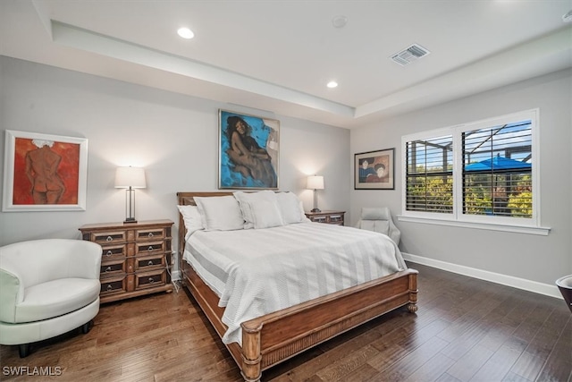 bedroom featuring a tray ceiling and dark hardwood / wood-style flooring