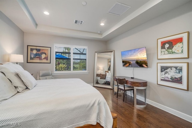 bedroom with a raised ceiling and dark hardwood / wood-style flooring