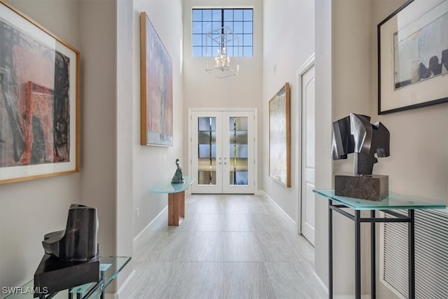 entrance foyer featuring a high ceiling, french doors, and a notable chandelier