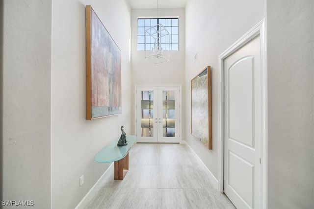 entrance foyer with french doors, a notable chandelier, and a towering ceiling