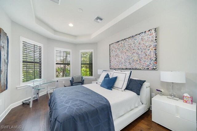 bedroom featuring a tray ceiling and dark hardwood / wood-style flooring