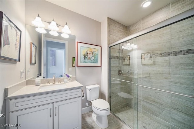 full bath featuring baseboards, toilet, a shower stall, and vanity