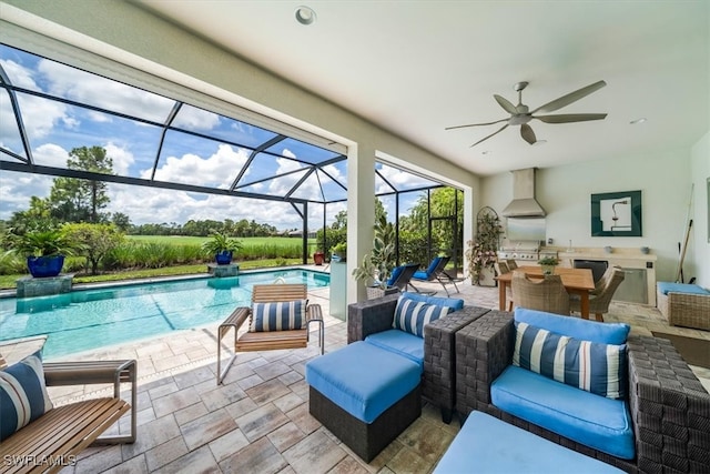 view of pool featuring a lanai, ceiling fan, a patio area, and an outdoor kitchen