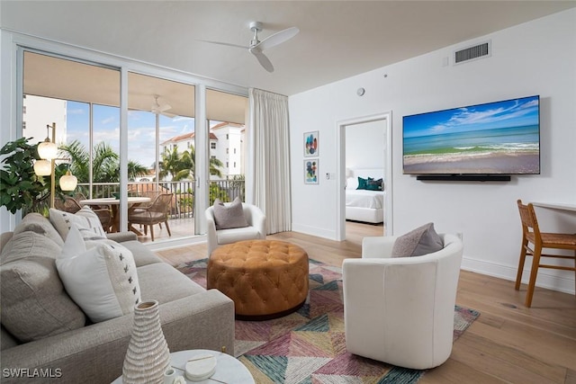 living room with expansive windows, ceiling fan, and light hardwood / wood-style flooring