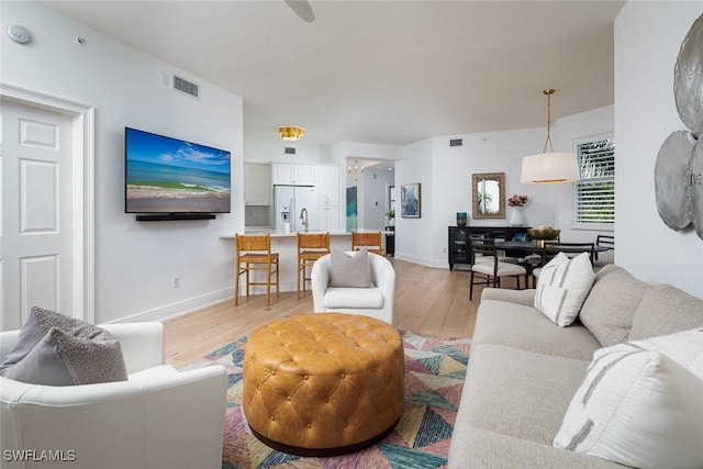 living room featuring sink and light hardwood / wood-style flooring