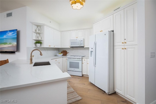 kitchen with white cabinetry, white appliances, kitchen peninsula, and sink