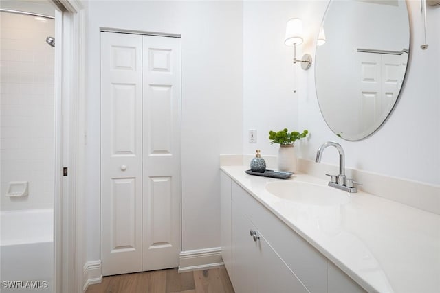 bathroom with hardwood / wood-style flooring, vanity, and shower / washtub combination