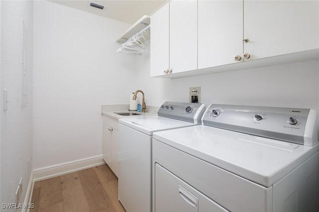 laundry room featuring sink, washer and clothes dryer, cabinets, and light wood-type flooring