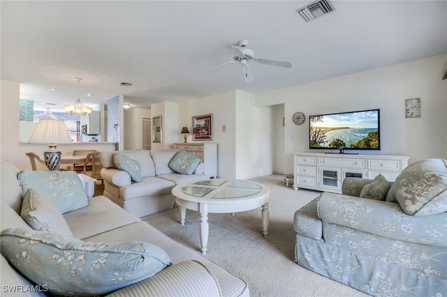 living room with ceiling fan with notable chandelier and light carpet