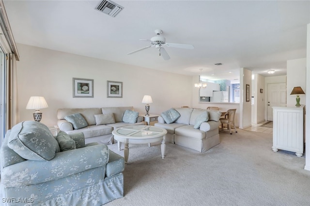 living room featuring ceiling fan with notable chandelier and light colored carpet