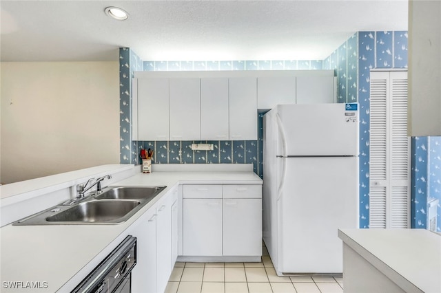 kitchen with sink, white cabinetry, light tile patterned floors, dishwasher, and white fridge