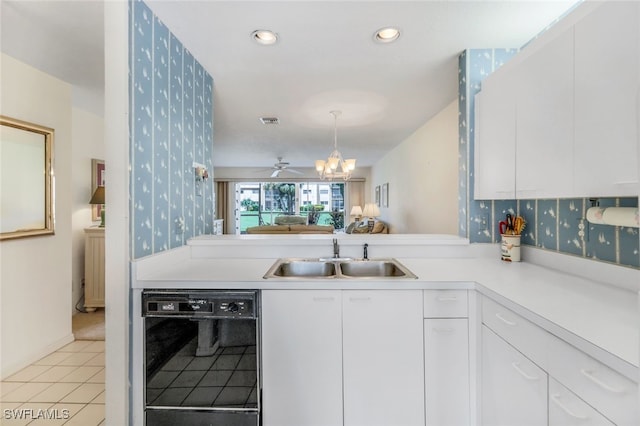 kitchen with light tile patterned flooring, decorative light fixtures, white cabinetry, dishwasher, and sink