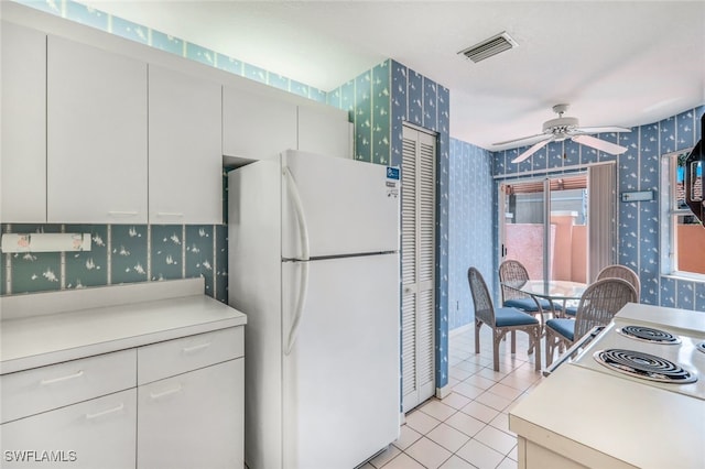 kitchen featuring white cabinetry, ceiling fan, white fridge, and light tile patterned floors