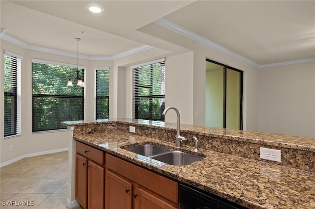 kitchen with a sink, pendant lighting, brown cabinetry, and dark stone countertops