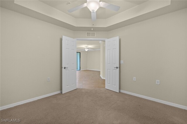 carpeted spare room featuring ceiling fan and a tray ceiling