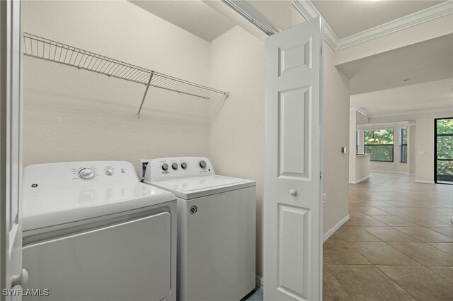 washroom featuring tile patterned flooring, ornamental molding, and washing machine and clothes dryer