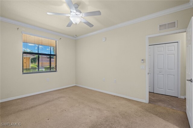 spare room featuring ceiling fan, crown molding, and light colored carpet