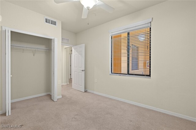 unfurnished bedroom featuring ceiling fan, light carpet, and a closet