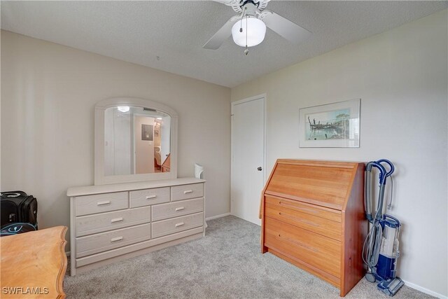 carpeted bedroom featuring ceiling fan and a textured ceiling