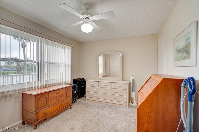 bedroom with ceiling fan, light carpet, multiple windows, and a textured ceiling