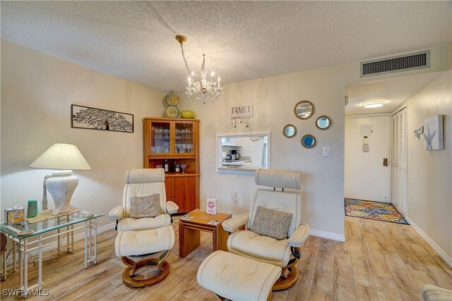 sitting room featuring a textured ceiling, an inviting chandelier, and light hardwood / wood-style floors