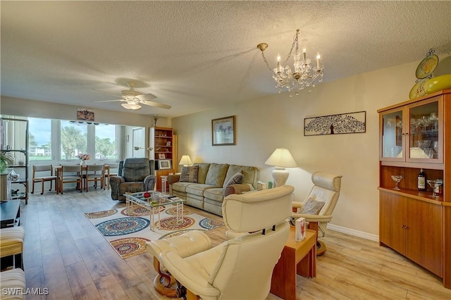 living room featuring ceiling fan with notable chandelier, a textured ceiling, and light wood-type flooring