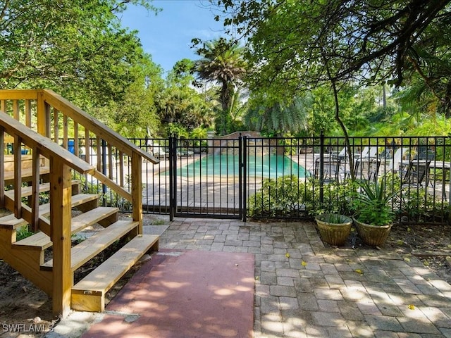 view of gate with a patio, a community pool, and fence