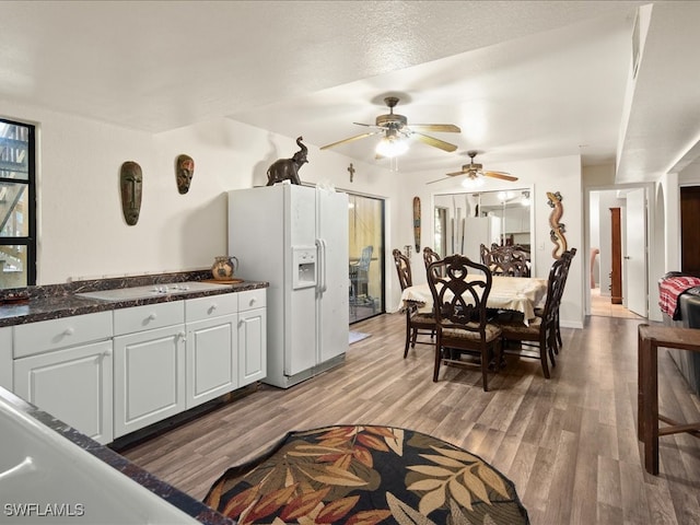 kitchen with white cabinetry, hardwood / wood-style floors, white refrigerator with ice dispenser, and ceiling fan