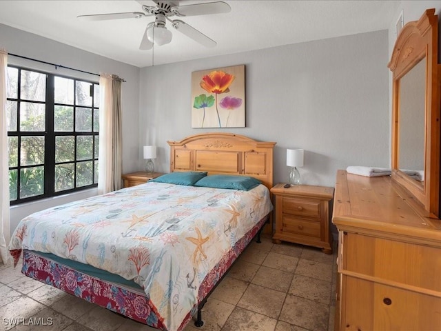 bedroom with ceiling fan and stone tile floors