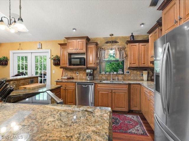 kitchen featuring a sink, appliances with stainless steel finishes, backsplash, dark wood-style floors, and brown cabinetry