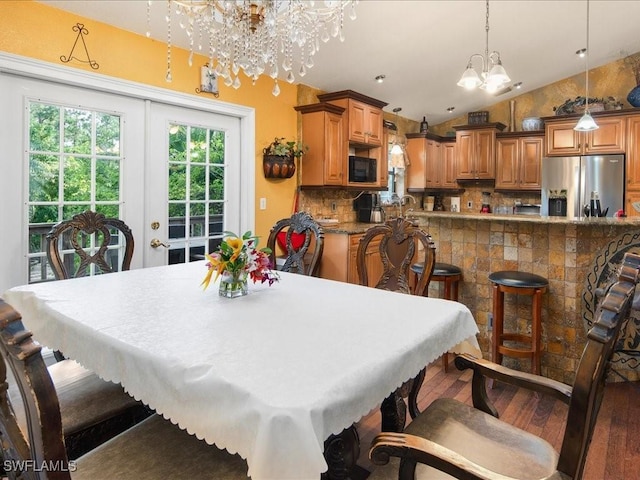 dining room featuring lofted ceiling, french doors, a notable chandelier, and wood finished floors