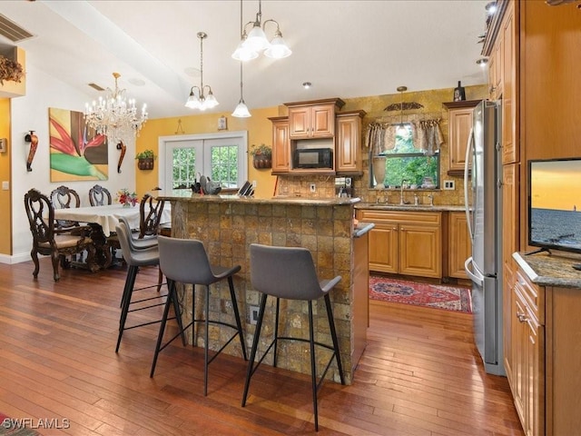 kitchen with black microwave, a breakfast bar area, a sink, and a wealth of natural light