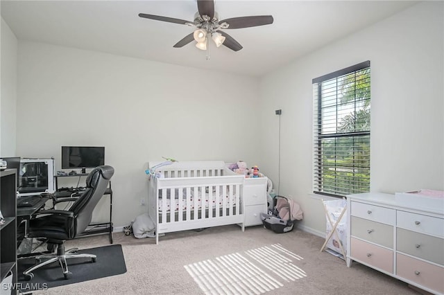 bedroom featuring light carpet, a crib, and ceiling fan