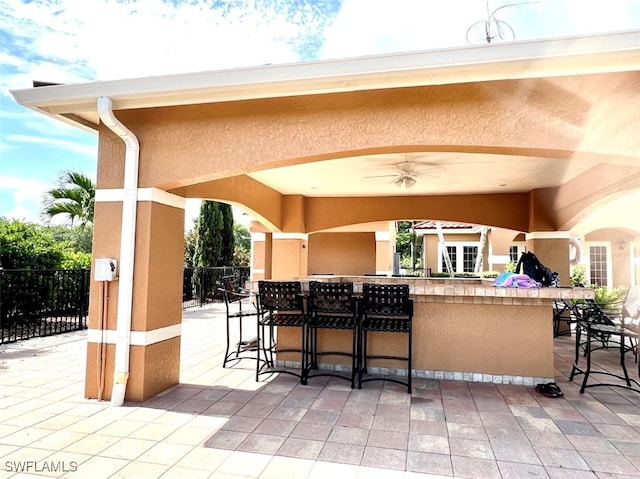 view of patio / terrace with ceiling fan and a bar