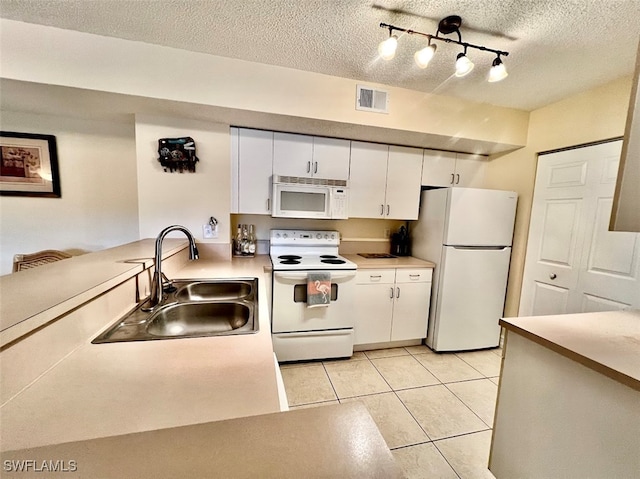 kitchen with a textured ceiling, white appliances, track lighting, sink, and white cabinetry