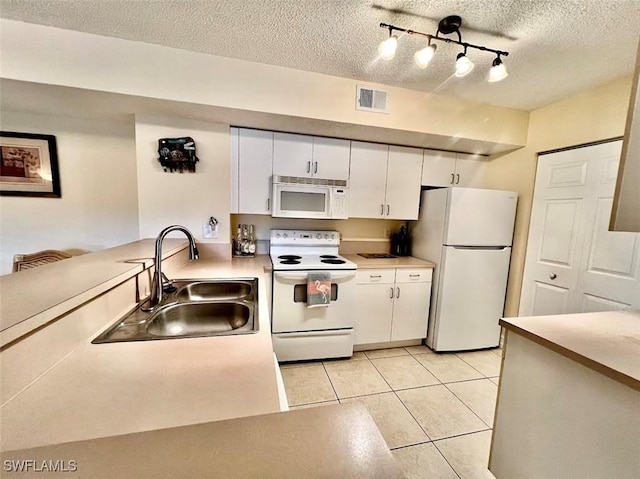 kitchen with white appliances, a sink, visible vents, white cabinetry, and light countertops