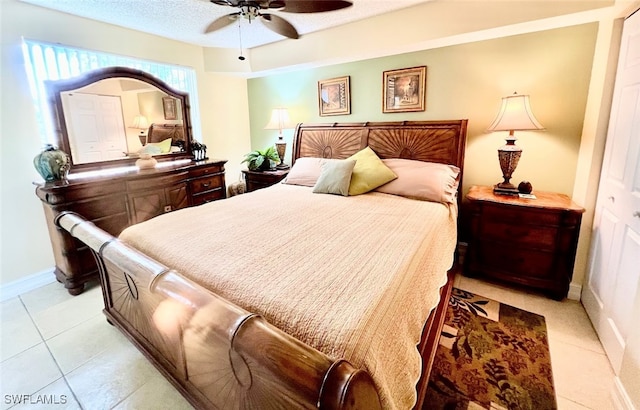 bedroom featuring ceiling fan, a textured ceiling, light tile patterned floors, and a closet