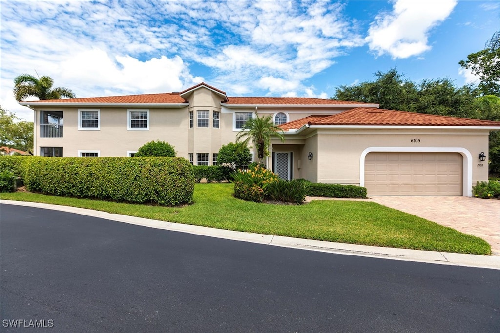 mediterranean / spanish home featuring a garage and a front yard